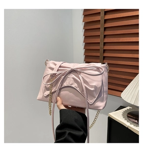 Close-up of pink pleated bow bag with elegant gold chain strap and soft leather texture
