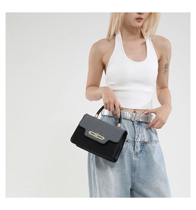 Detail of a vintage-style patchwork square bag with gold lock and textured flap on model