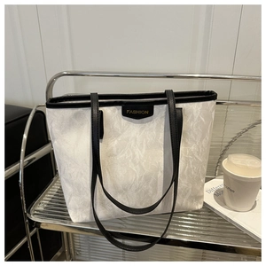 Detail showing the white wrinkled texture leather and FASHION label on the tote bag