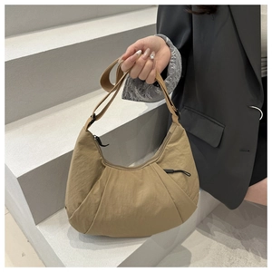 Detail of khaki crescent crossbody bag with nylon pleats and wide textile shoulder strap