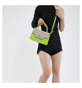 Detail of neon green crossbody bag with beige woven flap on black outfit model