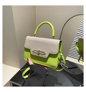 Detail view of lime green and beige canvas patchwork handbag with a gold metal lock
