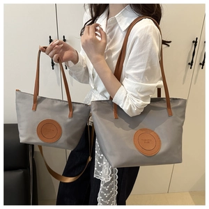 Comparison of large and small grey waterproof nylon tote bags with brown leather straps