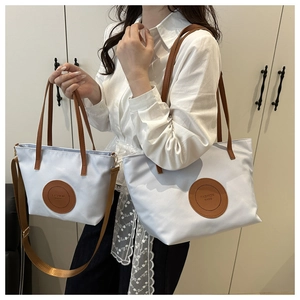 Detail view of water-resistant nylon tote bag with leather badge and premium stitching