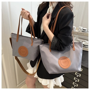 Detailed comparison of gray nylon tote bags in large and small sizes with leather handles
