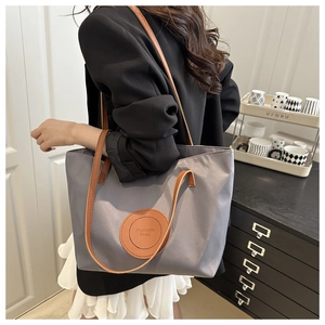 Detail view of stylish grey tote bag with brown leather accents on shoulder strap