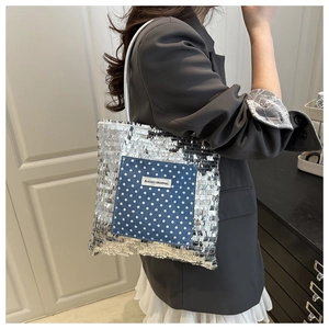 Detail of silver sequin tote bag with a navy polka dot pocket and brand logo patch