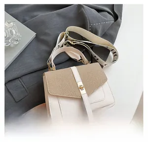 Détail du petit sac bandoulière avec mélange de matières et large sangle lettrée