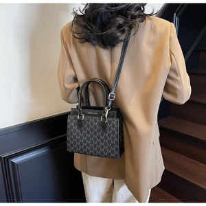 Close-up of a stylish black tote bag featuring M-pattern texture and detachable strap