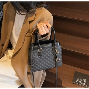 Detail of elegant black monogram tote bag featuring golden hardware and leather handles