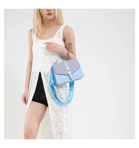 Détail du sac bandoulière bleu clair avec large sangle logo et fermoir tournant en métal