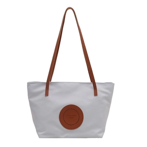 Minimalist grey tote bag with brown handles and a round fashion bags logo patch
