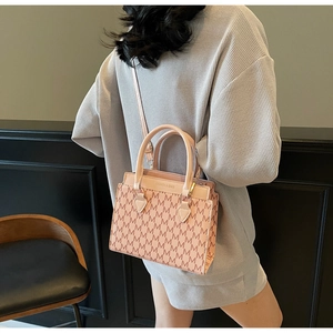 Detail of light pink tote bag featuring a repeating M monogram pattern and slim shoulder strap