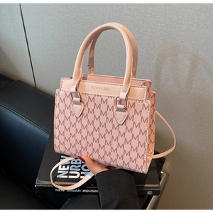 Close-up of pink monogram tote bag with gold lettering on premium book background