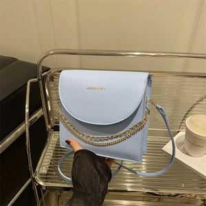 Hellblaue Klappentasche aus Kunstleder mit Goldketten und elegantem Schultergurt