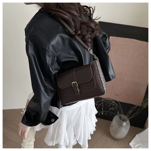Detail of dark brown crossbody bag featuring woven texture and adjustable shoulder strap