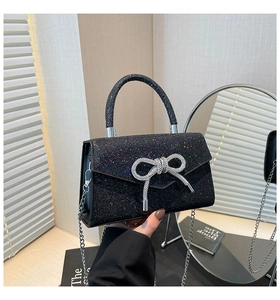 Détail de la pochette de soirée noire pailletée avec nœud strass et chaîne argent