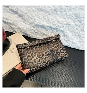 Close-up of leopard print clutch with fold-over design and metallic hardware on textured surface
