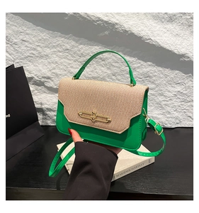 Dettaglio di pelle verde e tessuto intrecciato beige con chiusura dorata sulla borsa