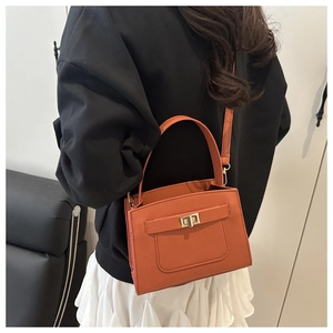 Vista laterale di una donna con borsa a tracolla arancione e chiusura dorata fine