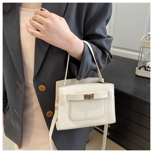 Close-up detail of cream textured leather handbag with gold twist-lock and shoulder strap