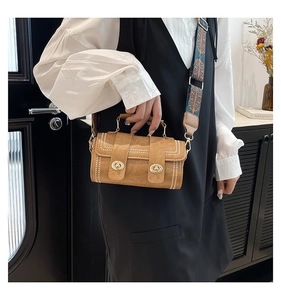 Close-up of brown cylindrical handbag featuring gold twist locks and metal rivet details