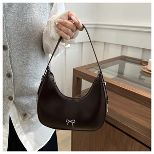 Detail of dark brown crescent hobo bag with a silver metal bow and smooth matte texture