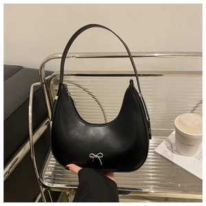 Close-up of black matte faux leather shoulder bag with silver metallic bow detail