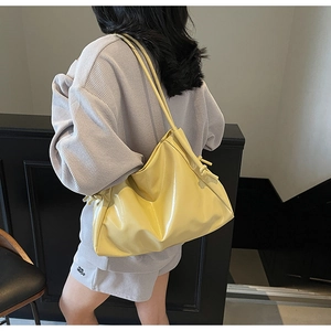 Detail view of glossy yellow leather tote bag with stylish side knotting details