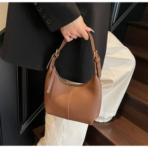 Detail of a brown leather hobo bag with vertical stitching and gold-toned zipper hardware