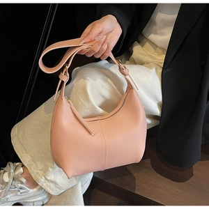 Close-up of minimalist half-moon shoulder bag in pink leather with fine stitching
