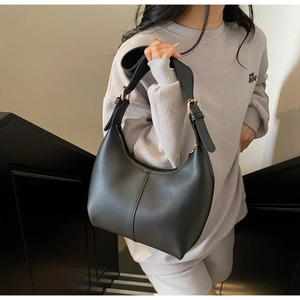 Detailed view of black leather hobo bag featuring wide straps and golden metal buckles