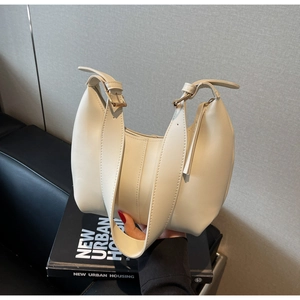Detailed close-up of cream underarm bag featuring wide adjustable strap and gold buckle