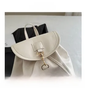 Close-up of off-white faux leather backpack with gold metal hook closure and top handle