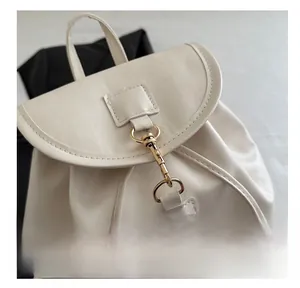 Detail of premium white leather backpack featuring a shiny gold metal lobster clasp hook