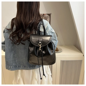 Detail view of a vintage black leather backpack with drawstring closure and metal buckle