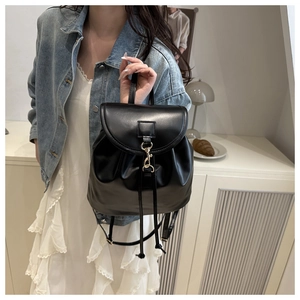 Detail of black faux leather backpack with gold hook buckle and drawstring closure