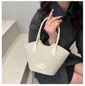 Detail showing the white woven bucket bag with elegant handles and a fashion metal plaque