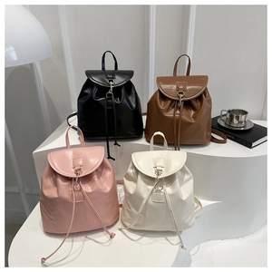 Detail of four PU leather backpacks in black, caramel, pink, and beige on white stands