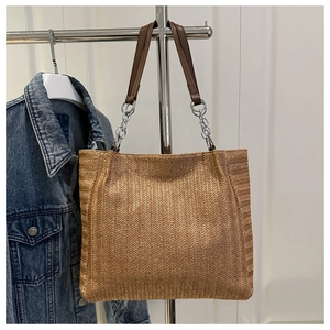 Detail of herringbone weave straw tote with brown leather and silver chain strap