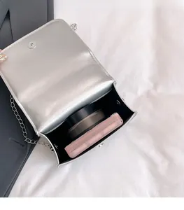 Macro view of the silver mini square bag showing interior storage for cosmetics