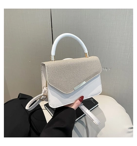 Detail of white leather and khaki woven texture on shoulder bag with silver metal buckle