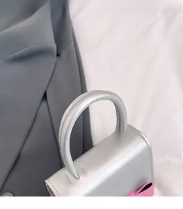 Detail of silver matte girls mini handbag featuring thick handle and pink bow decoration