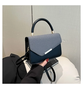 Detail of contrast stitch fabric flap and black leather bag with gold metal buckle