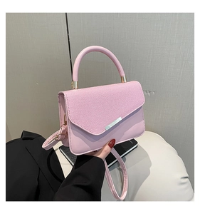 Close-up of pink leather handbag with striped texture flap and gold hardware details