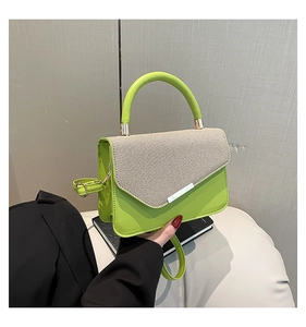 Detail of green leather and beige woven fabric on a stylish crossbody handbag