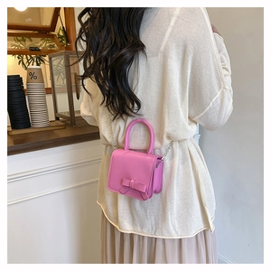 Detailed view of a pink girls' mini crossbody bag with a bow and metal chain strap