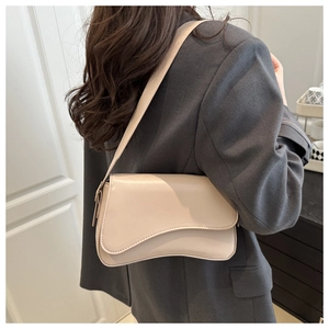 Detail of minimalist cream leather underarm bag with asymmetrical curved flap design
