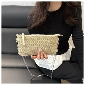 Détail d'une pochette tressée beige avec chaîne à boules argentées et fermeture éclair