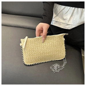 Détail d'un sac bandoulière beige tissé avec bordure perlée argentée et chaînette